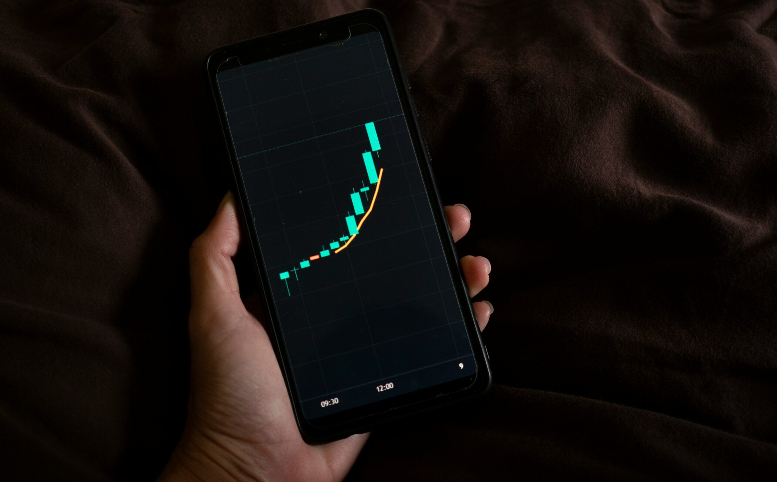 Person holding a phone displaying a financial growth chart — compound interest visualised